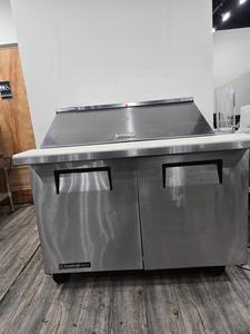 PREP TABLE - 48 IN PREP TABLE. 2 DOORS HINGED LID TO COVER CONTAINERS ON TOP. UNDERNEATH REFRIGERATION TO KEEP EXTRA FOODS AND INGREDIENTS COLD. RETAIL $1500.00